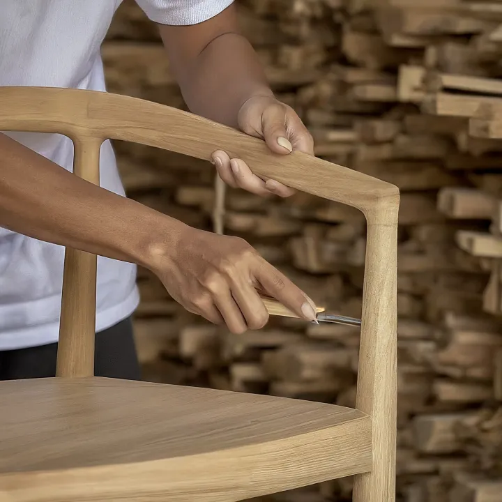Pengrajin furnitur sedang mengerjakan kursi kayu jati di workshop